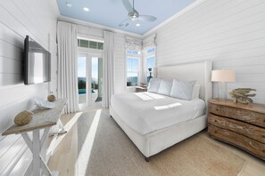 A modern bedroom with a large bed, a ceiling fan, a TV mounted on the wall, and a view of the ocean through the sliding glass doors. - 30A Stunner! Gulf Views, Private Pool, Beach & Golf Cart | Fall Now Booking! (Santa Rosa Beach)