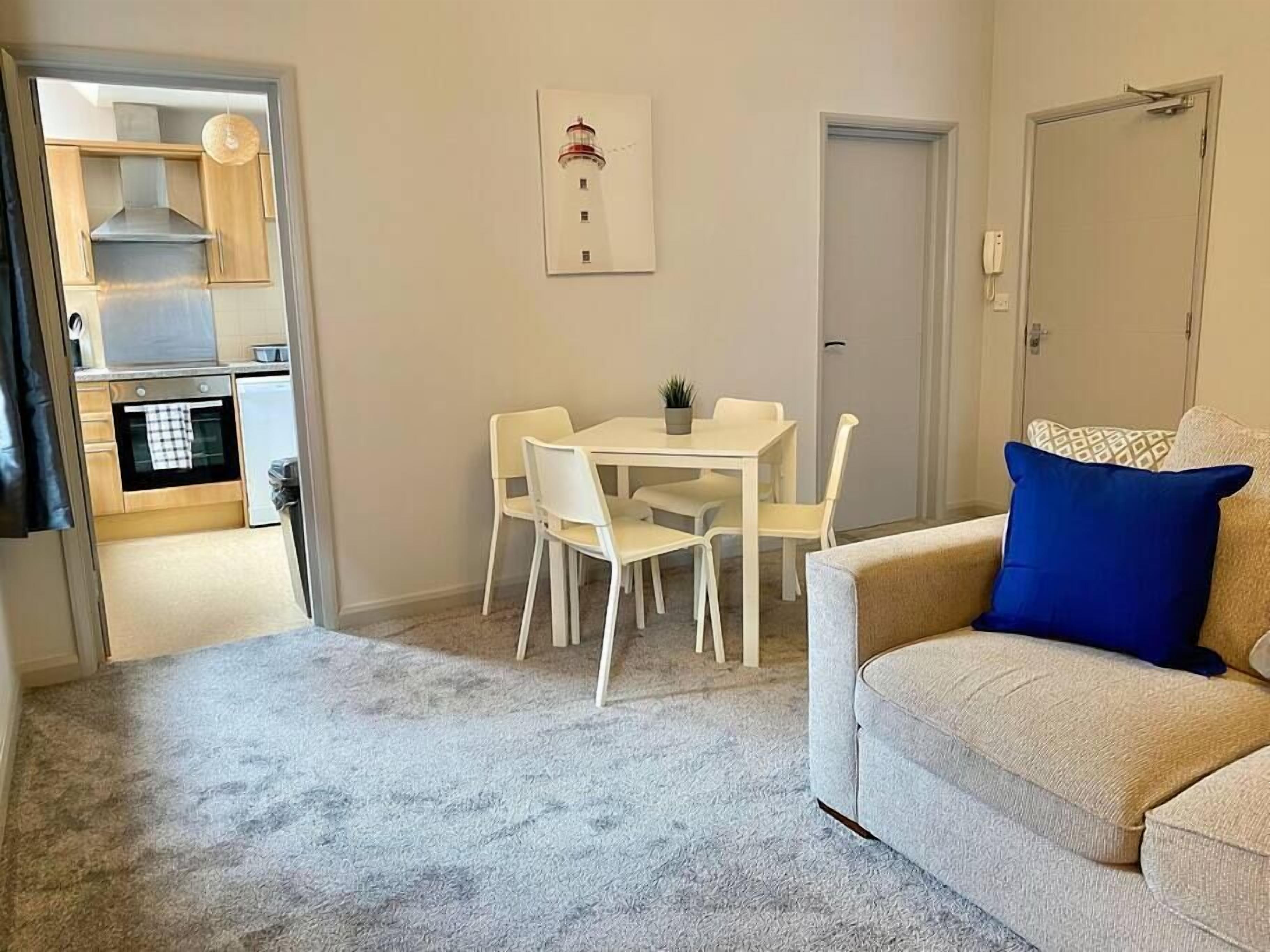 Un espace de vie compact comprenant un coin cuisine, un coin repas et un espace détente avec un canapé et une table.