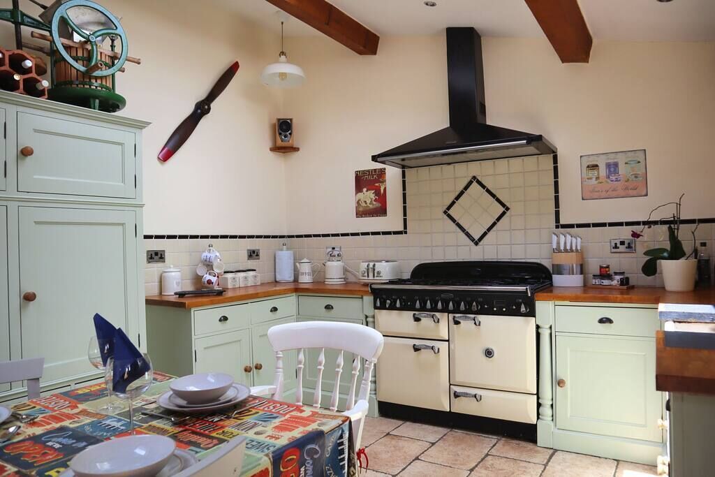 A kitchen with a stove, cabinets, and a dining area with a table set for two.