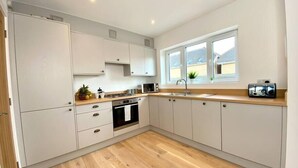 A modern kitchen with white cabinets, a wooden countertop, a built-in oven, and a window with a view of the outside.