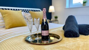 A bed with a champagne bottle, two glasses, and a tray.