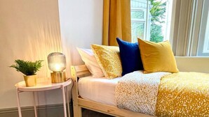 Ein Schlafzimmer mit einem Bett, einem Nachttisch mit Lampe und einem Blumentopf.