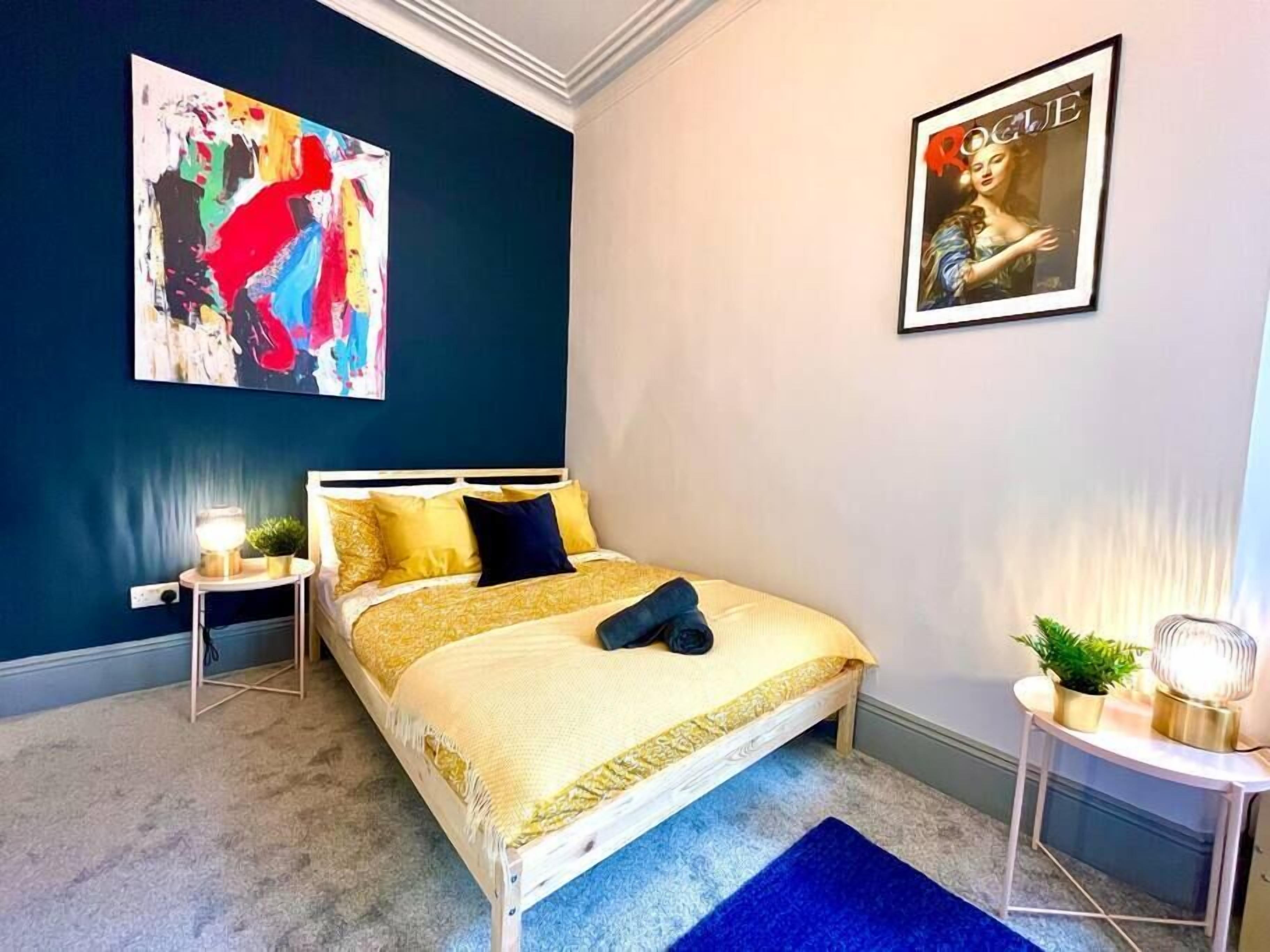 A bedroom with a bed, a nightstand, a lamp, and a poster on the wall.