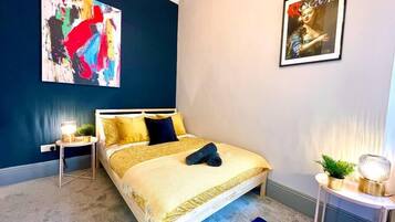 A bedroom with a bed, a nightstand, a lamp, and a poster on the wall.