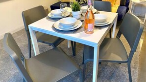 A dining area with a table set for two, including plates, glasses, and a bottle of water. - Funky Apartment - 5 minute walk to the beach! (Westbourne)