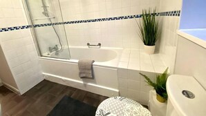 A bathroom with a glass-enclosed shower, a bathtub, a toilet, and a sink. - Funky Apartment - 5 minute walk to the beach! (Westbourne)