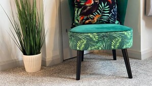 A teal armchair with a tropical leaf pattern and a toucan pillow, a tall green plant in a white pot, and a carpeted floor. - Funky Apartment - 5 minute walk to the beach! (Westbourne)