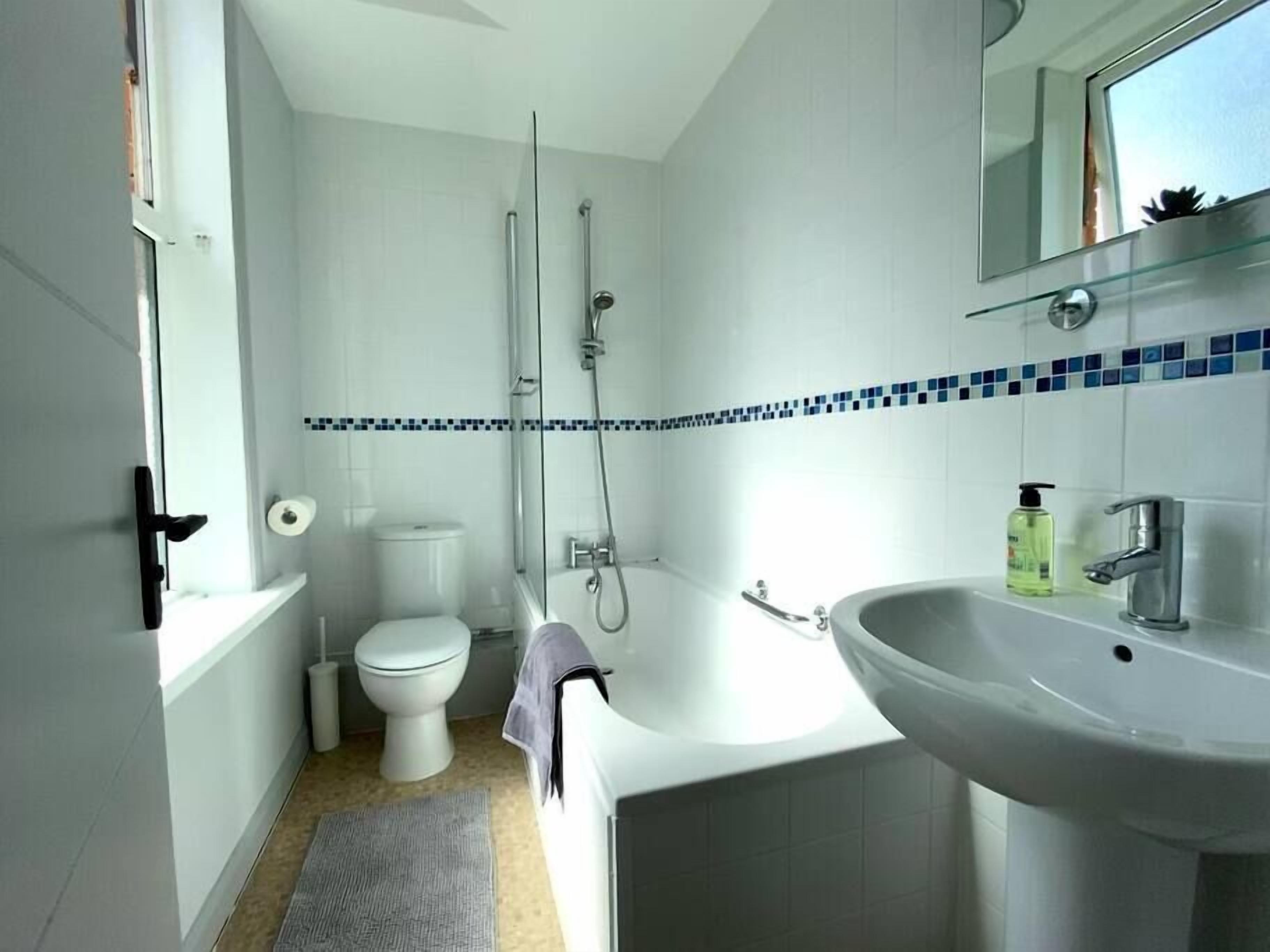 A modern bathroom with a toilet, shower, and sink.