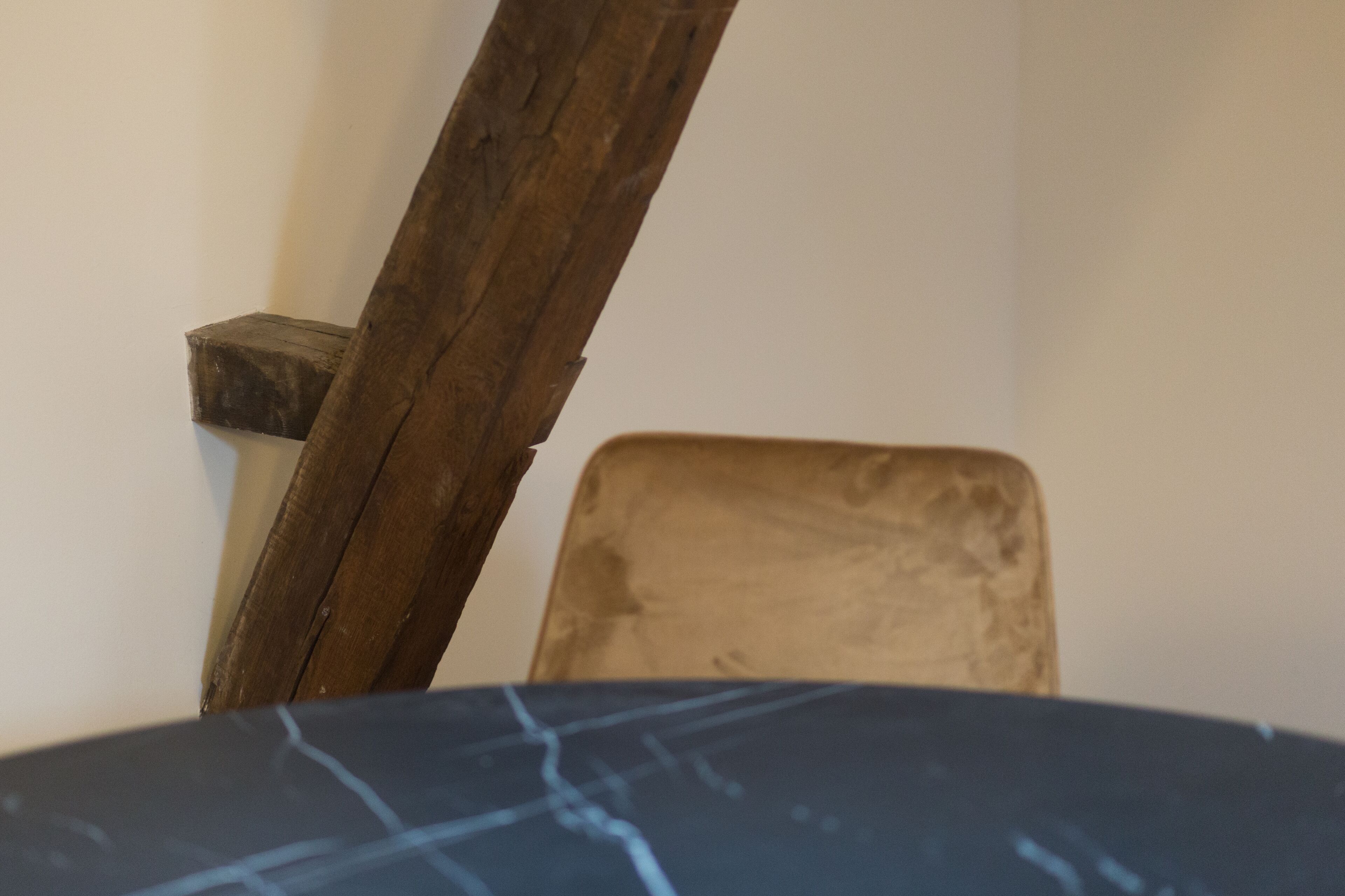 A corner of a room with a wooden chair and a dark-colored table.