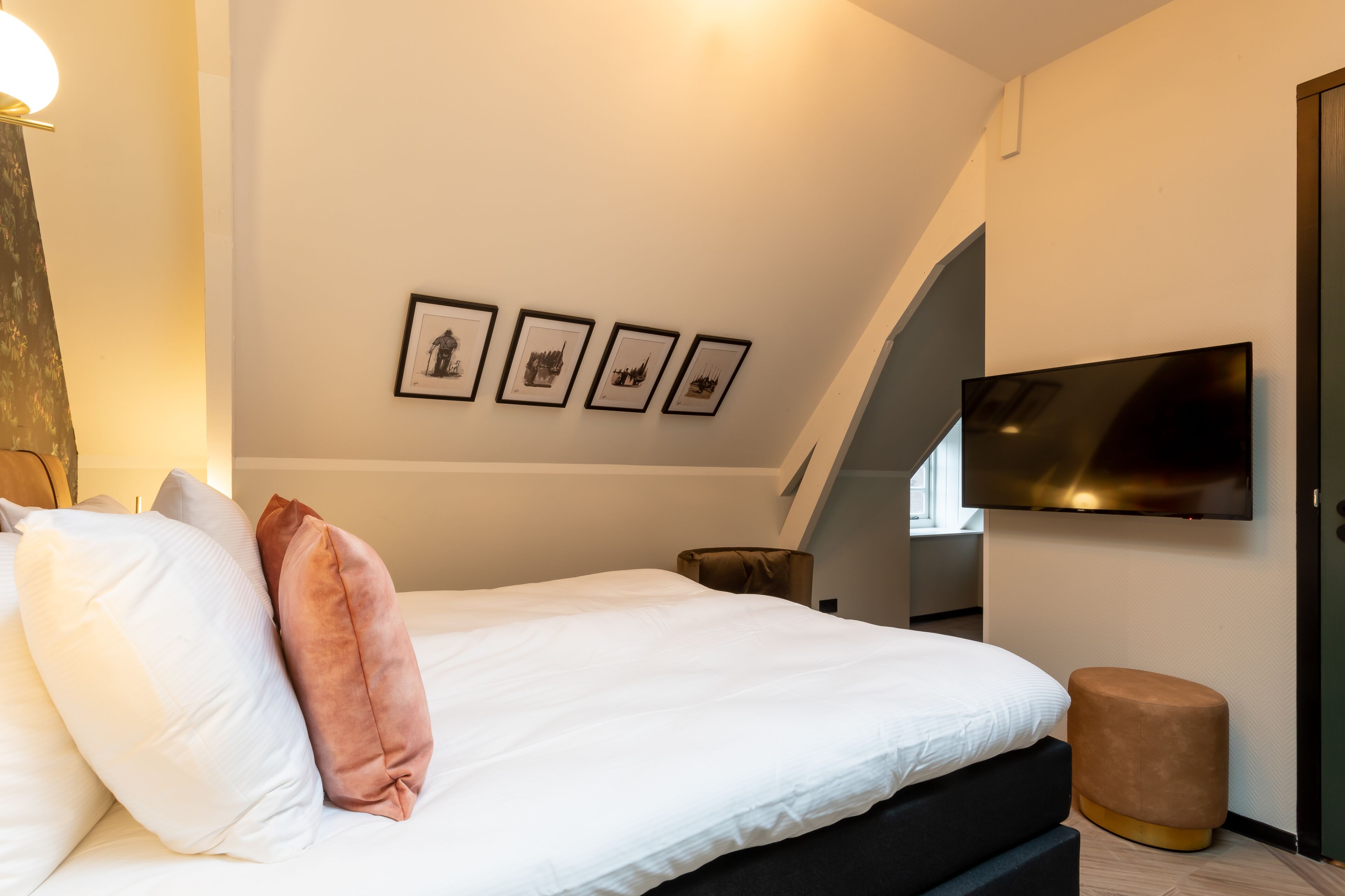 Un dormitorio moderno con cama, televisor de pantalla plana y cuadros enmarcados en la pared.