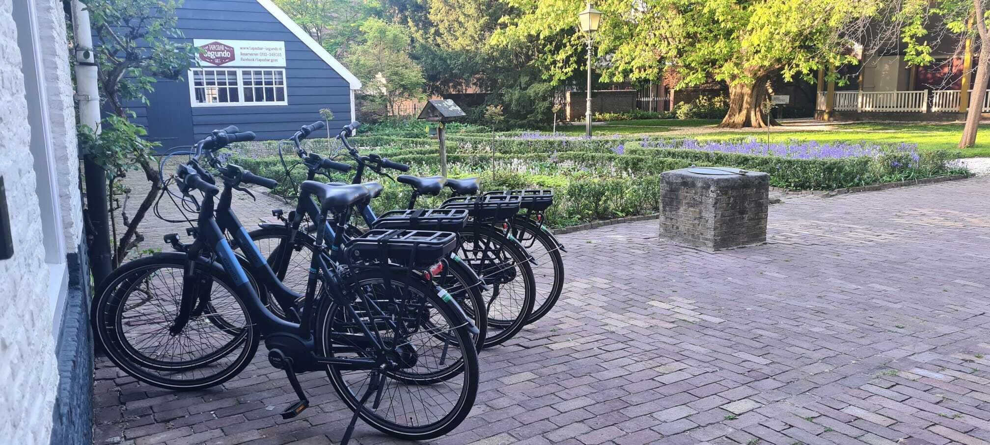 A row of stationary bicycles parked outside a building with a signboard.