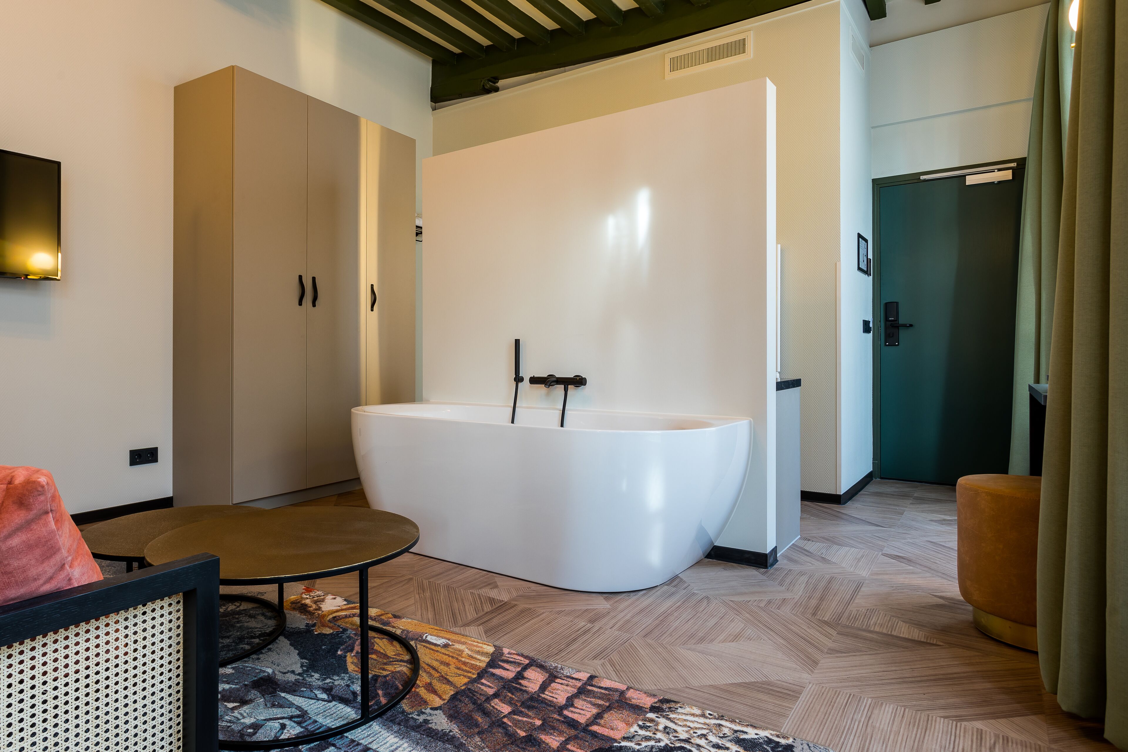 Une salle de bain moderne avec une baignoire sur pieds, un plancher en bois et une grande armoire.