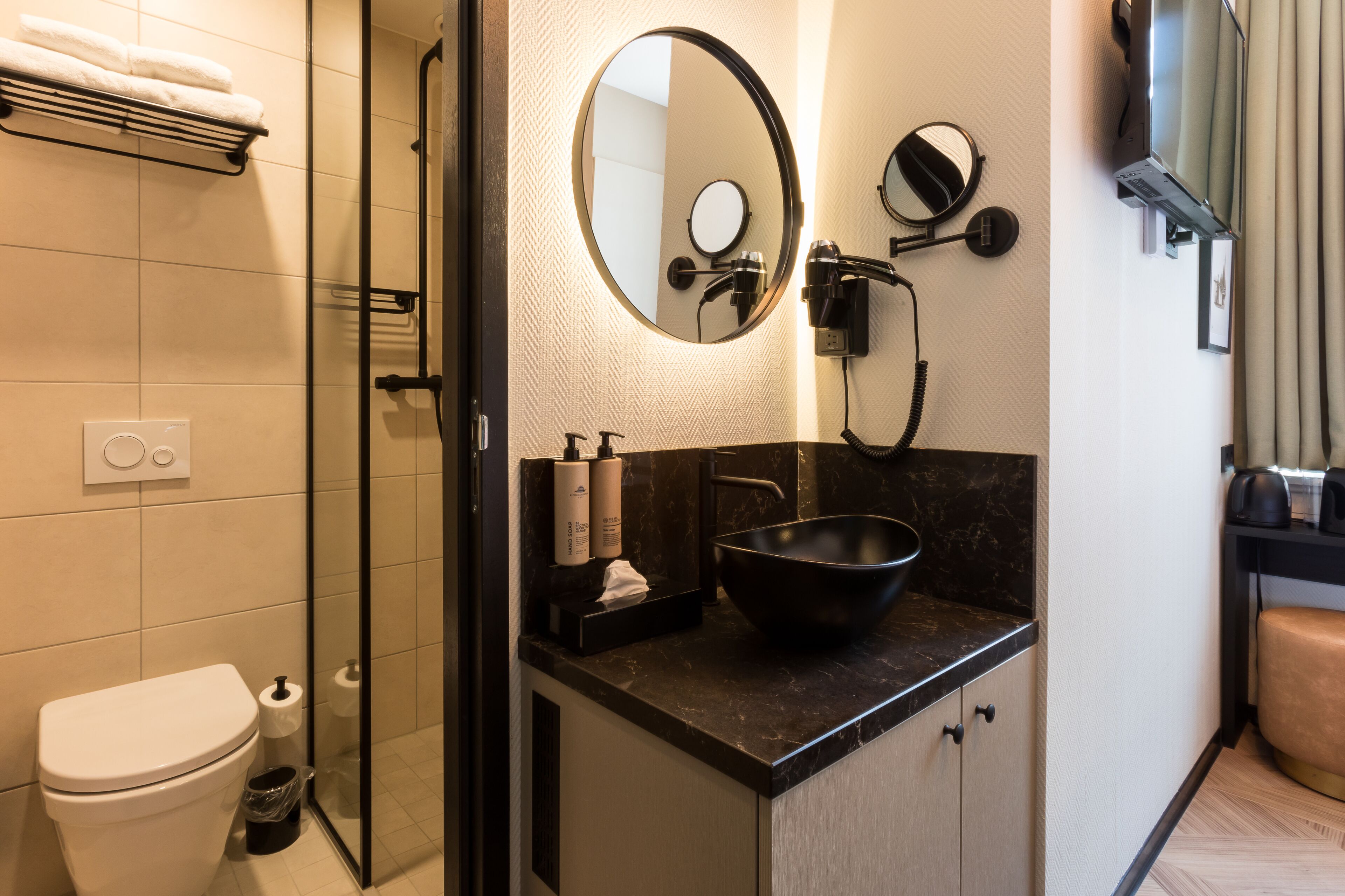 Ein modernes Badezimmer mit einem schwarzen Waschbecken, einem großen Spiegel und einer Duschkabine aus Glas.