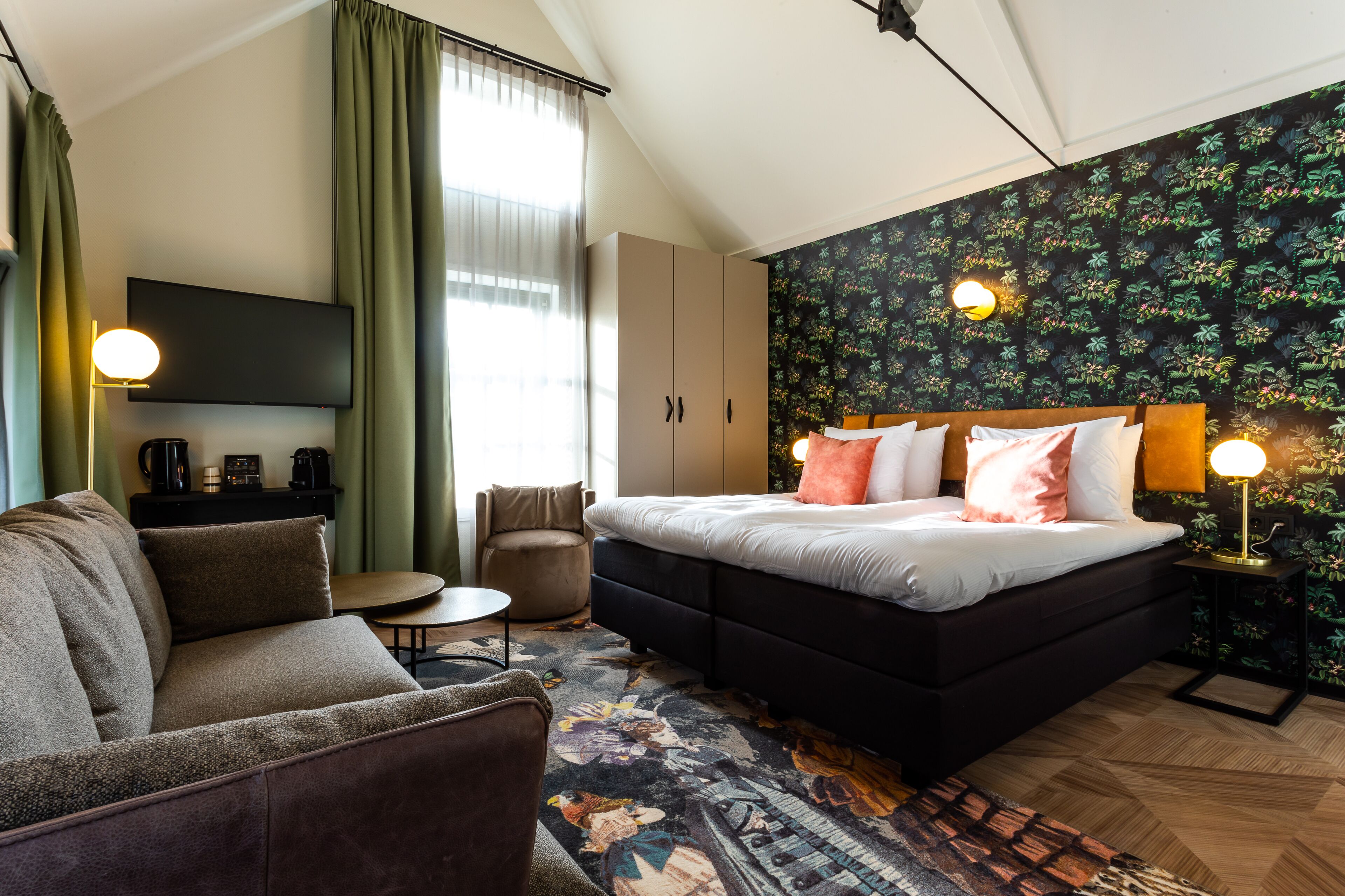 A modern hotel room with a large bed, a sofa, a small table, and a TV.