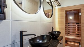 A modern bathroom with two black sinks, a black faucet, and a wooden sauna visible through a glass door. - Boutique Hotel Rijks I Kloeg Collection (Goes)