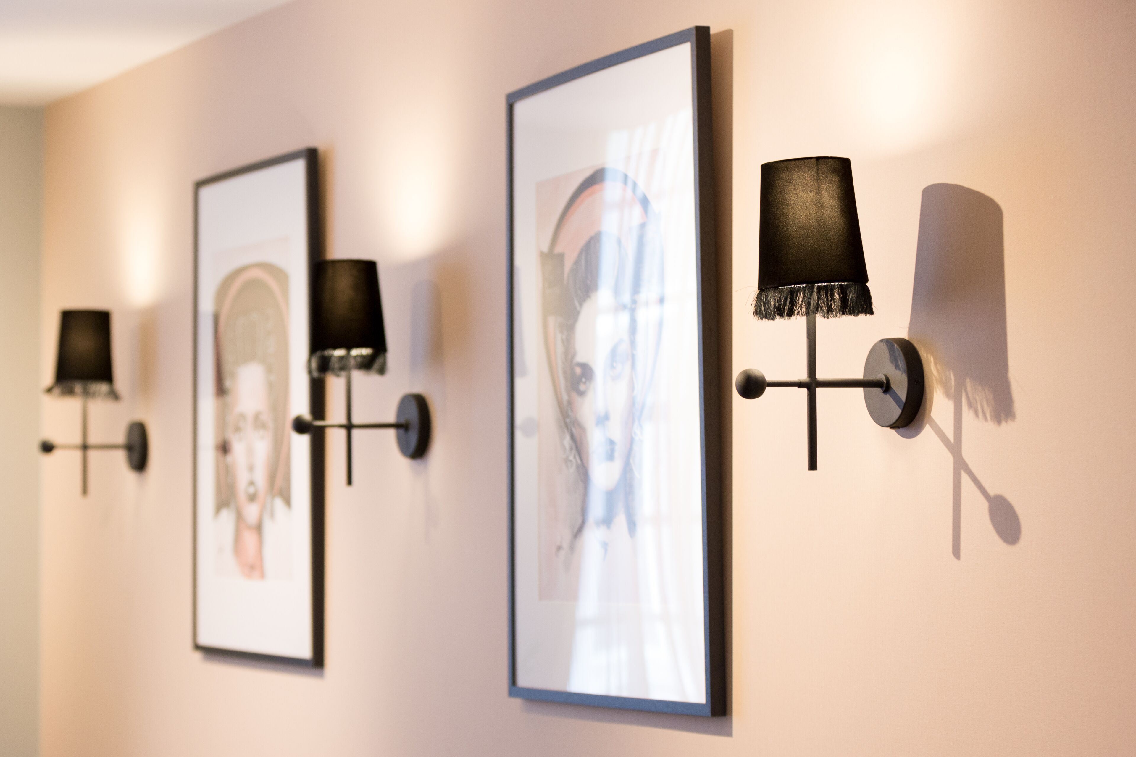 Wall-mounted lamps and framed artwork in a hallway.