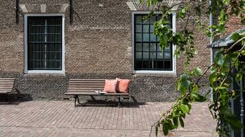 A brick building with two windows and a bench with cushions.