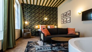 A modern living room with a sofa, a round coffee table, and a large white bathtub. - Boutique Hotel Rijks I Kloeg Collection (Goes)
