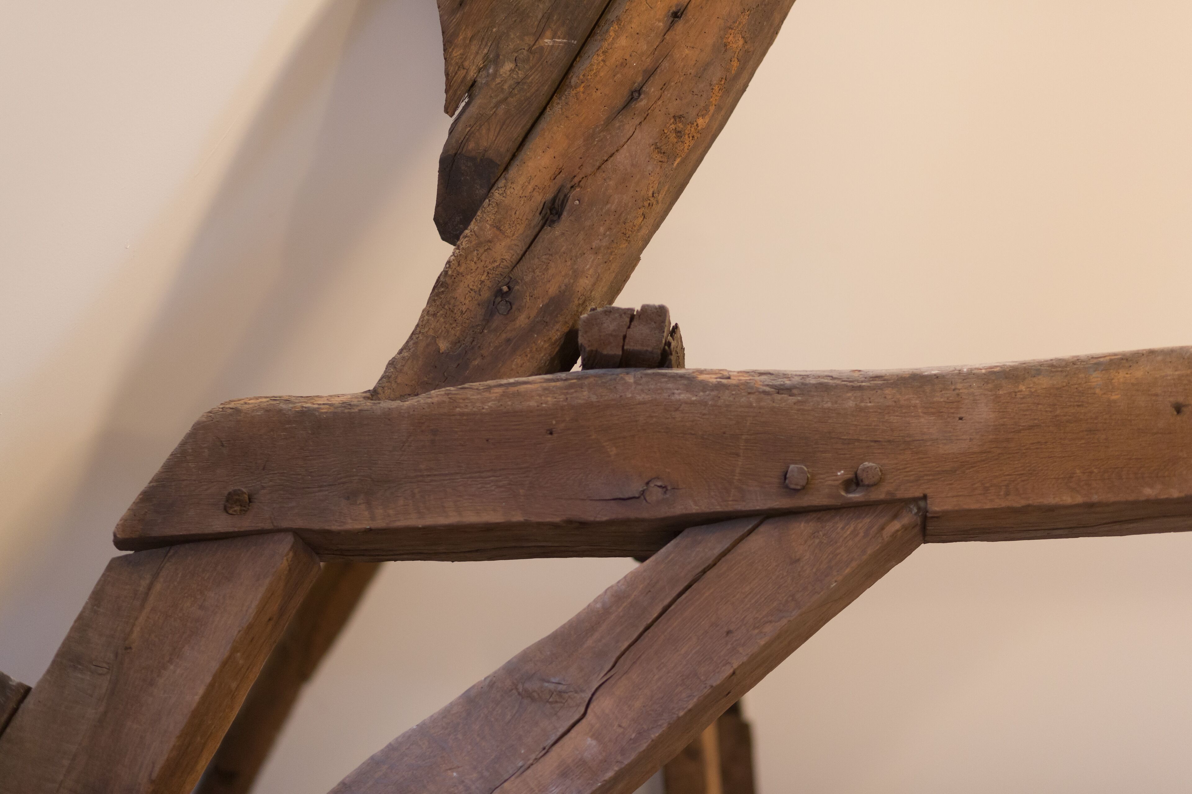 Primer plano de una estructura de madera con una viga de soporte diagonal y un sujetabrazos metálico.