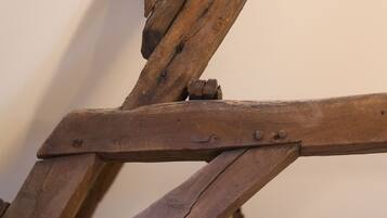 Primer plano de una estructura de madera con una viga de soporte diagonal y un sujetabrazos metálico.