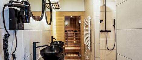 A modern bathroom with a black sink, a hairdryer, and a towel rack.
