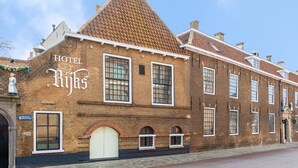 A historic building with a sign reading "HOTEL Rijks". It features large windows, a prominent arched entrance, and a tiled roof. - Boutique Hotel Rijks I Kloeg Collection (Goes)