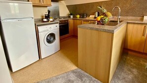 Una cocina compacta con microondas, lavadora, fregadero y armarios de madera.
