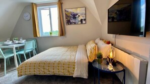 Un dormitorio con cama, escritorio, silla, televisión y ventana.