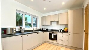 Una cocina moderna con armarios de colores claros, encimera negra y suelo de madera.