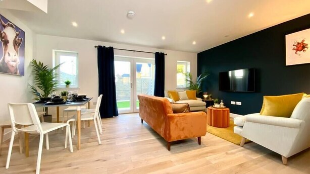 A modern living room with a sofa, chairs, a dining table, and a TV.