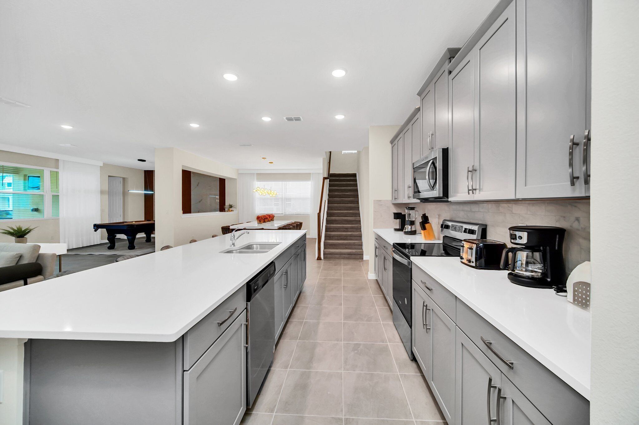 Una cocina moderna con una isla central, armarios grises y electrodomésticos de acero inoxidable.