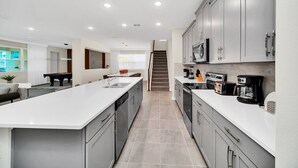 Una cocina moderna con una isla central, armarios grises y electrodomésticos de acero inoxidable.