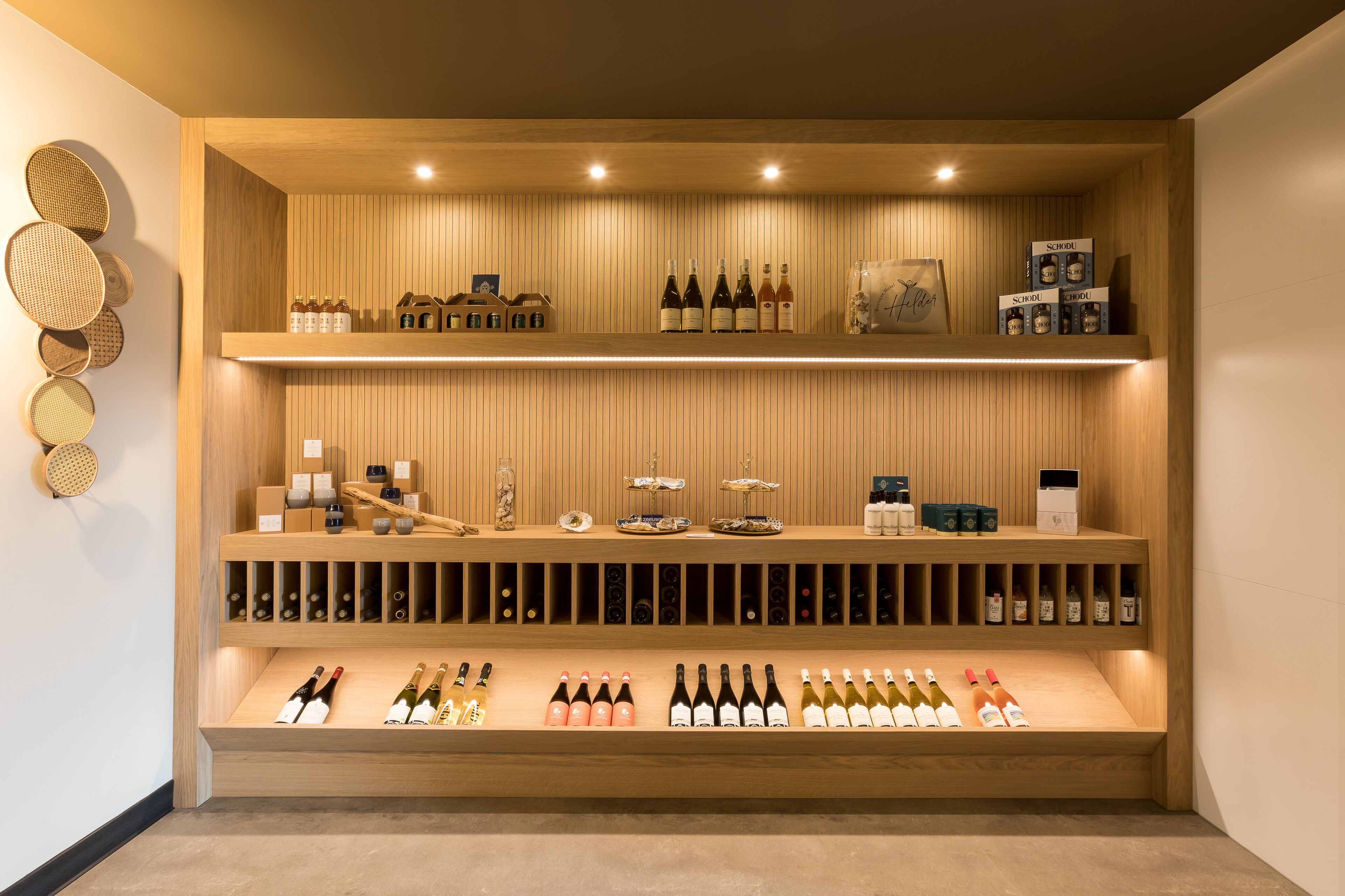 A wine cellar with wooden shelves and racks, displaying various bottles and wine accessories.