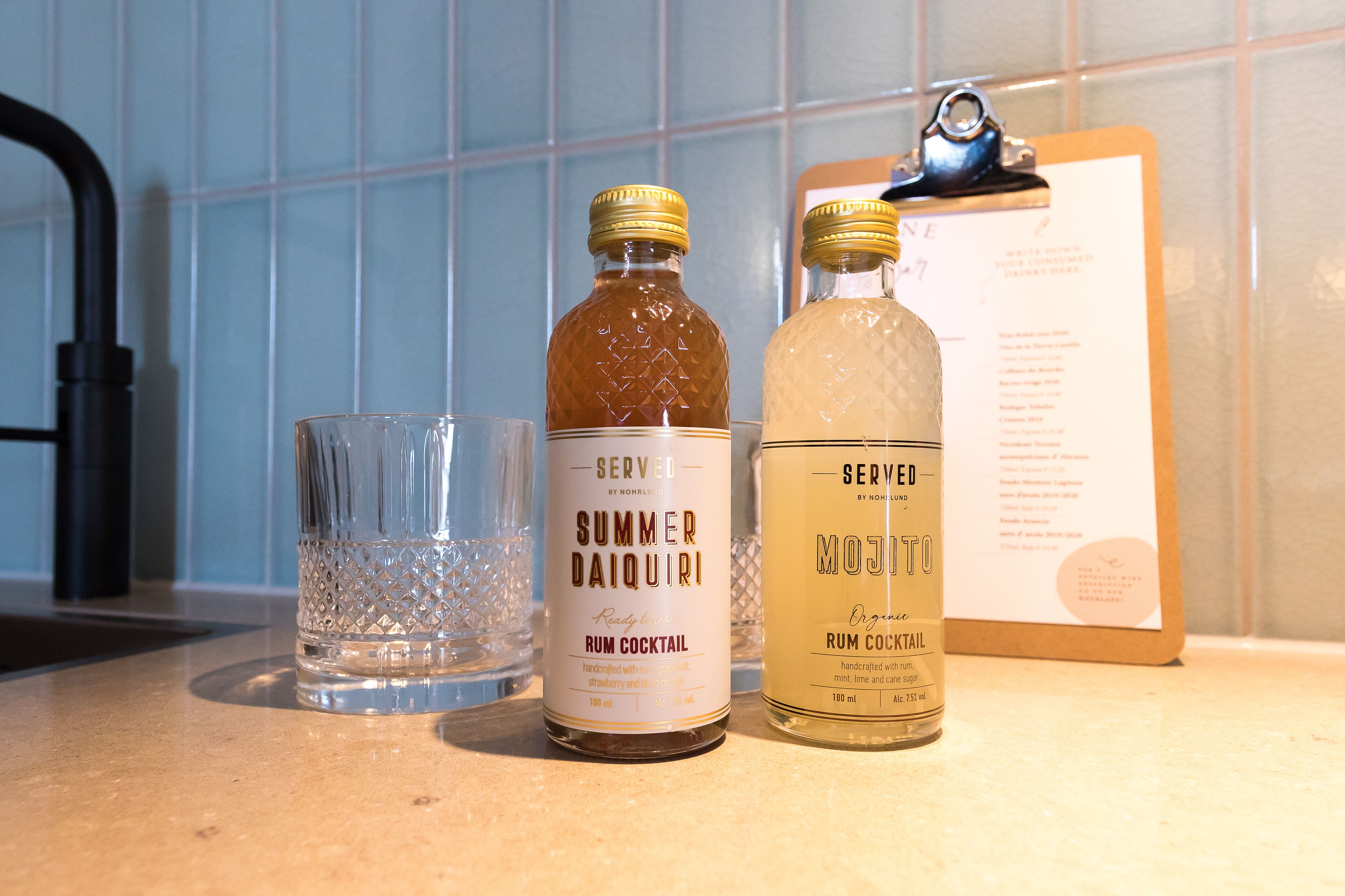 Two bottles of rum cocktail and a glass on a countertop.