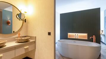 Un baño moderno con una bañera independiente, un espejo redondo y un lavabo sobre encimera.
