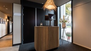 A modern reception area with a wooden reception desk, a mounted television, and a hanging light fixture.