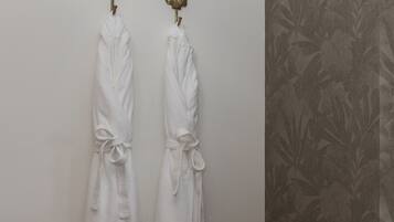 A bathroom with a bathtub, two towels hanging on hooks, and a patterned wallpaper.