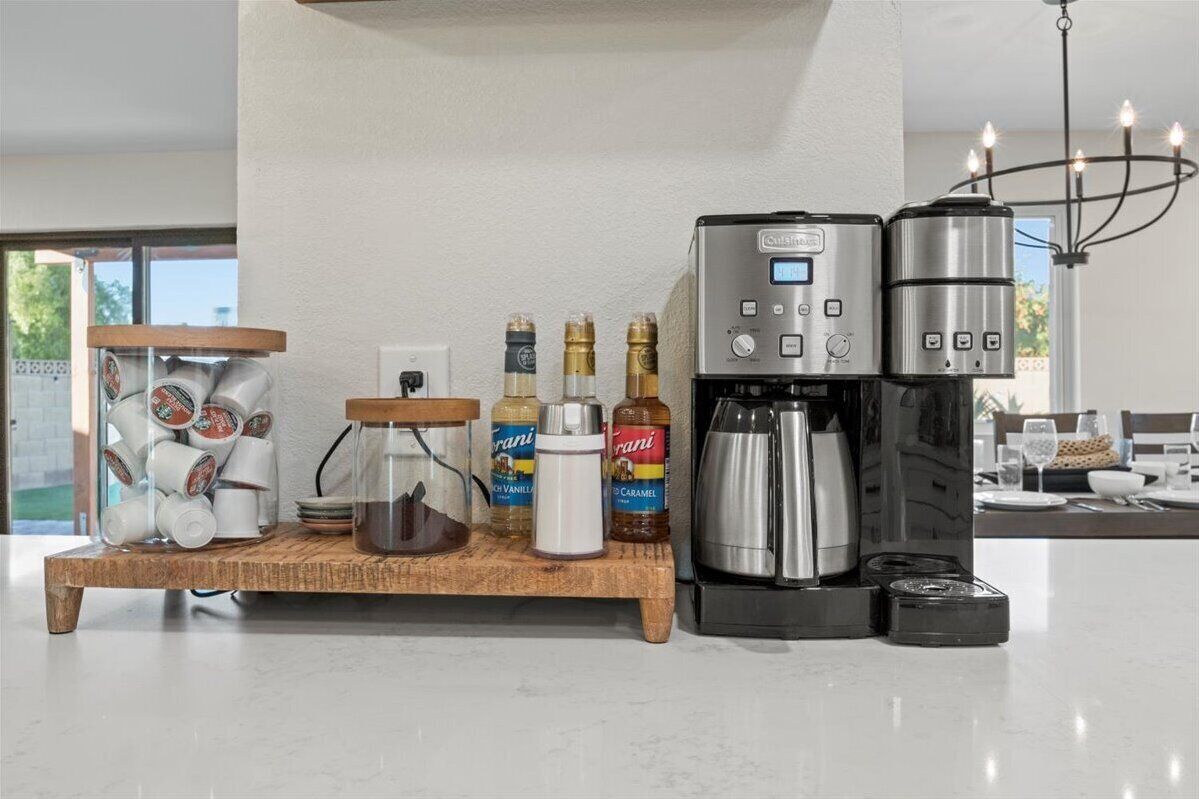 Eine Küche mit Kaffeemaschine, Kaffeekanne und Kaffeemühle auf einer Holzablage.
