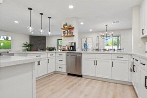 A modern kitchen with white cabinetry, a dishwasher, pendant lights, and a herringbone-patterned backsplash. - Backyard Paradise w/ Hot Tub & Heated Pool ! (Scottsdale)