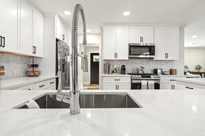 Enjoy cooking in this well-equipped kitchen with a refrigerator, microwave, and stove, complemented by a large sink and ample cabinetry.