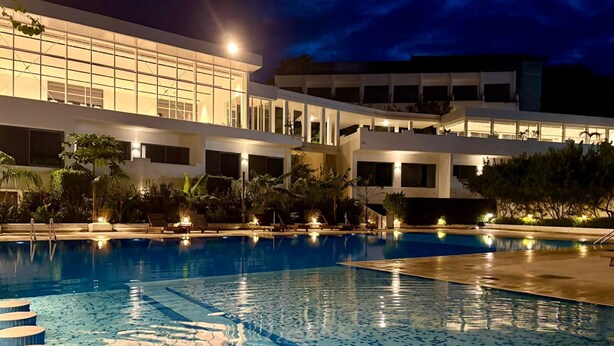 A swimming pool with clear blue water, surrounded by a modern building with multiple floors and large windows. - The Lead Hotel (Freetown)