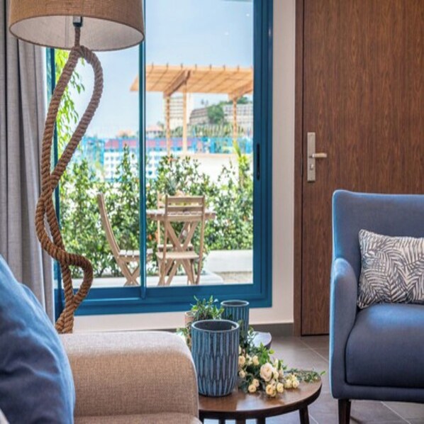 Ein modernes Zimmer mit einer Couch, einer Lampe, einem Tisch mit Blumen und Blick auf einen Außenbereich mit Holzkonstruktion.