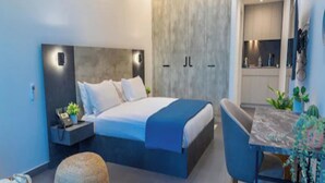 Une chambre moderne avec un grand lit, une table de chevet et un petit coin cuisine.