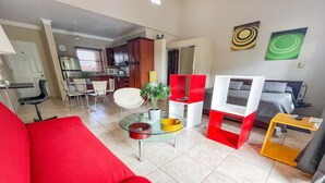 A living room with a red sofa, a glass coffee table, a TV, and a yellow side table. - Beautiful Studio in Ocean Dream Cabarete (Cabarete)