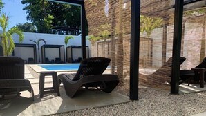 Ein Poolbereich mit Liegestühlen, einem Pool und einer Bambus-Umzäunung.
