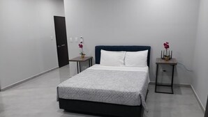 Ein modernes Schlafzimmer mit einem großen Bett, einem dunklen Kopfteil und zwei Nachttischen mit Dekoration.