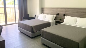 Habitación de hotel con dos camas, una silla, una mesita y una puerta corrediza de vidrio al exterior.