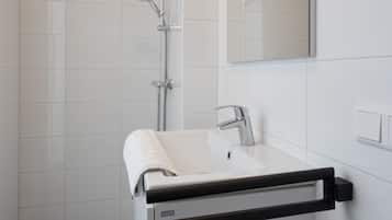 Ein modernes Badezimmer mit Waschbecken, Spiegel und Dusche.