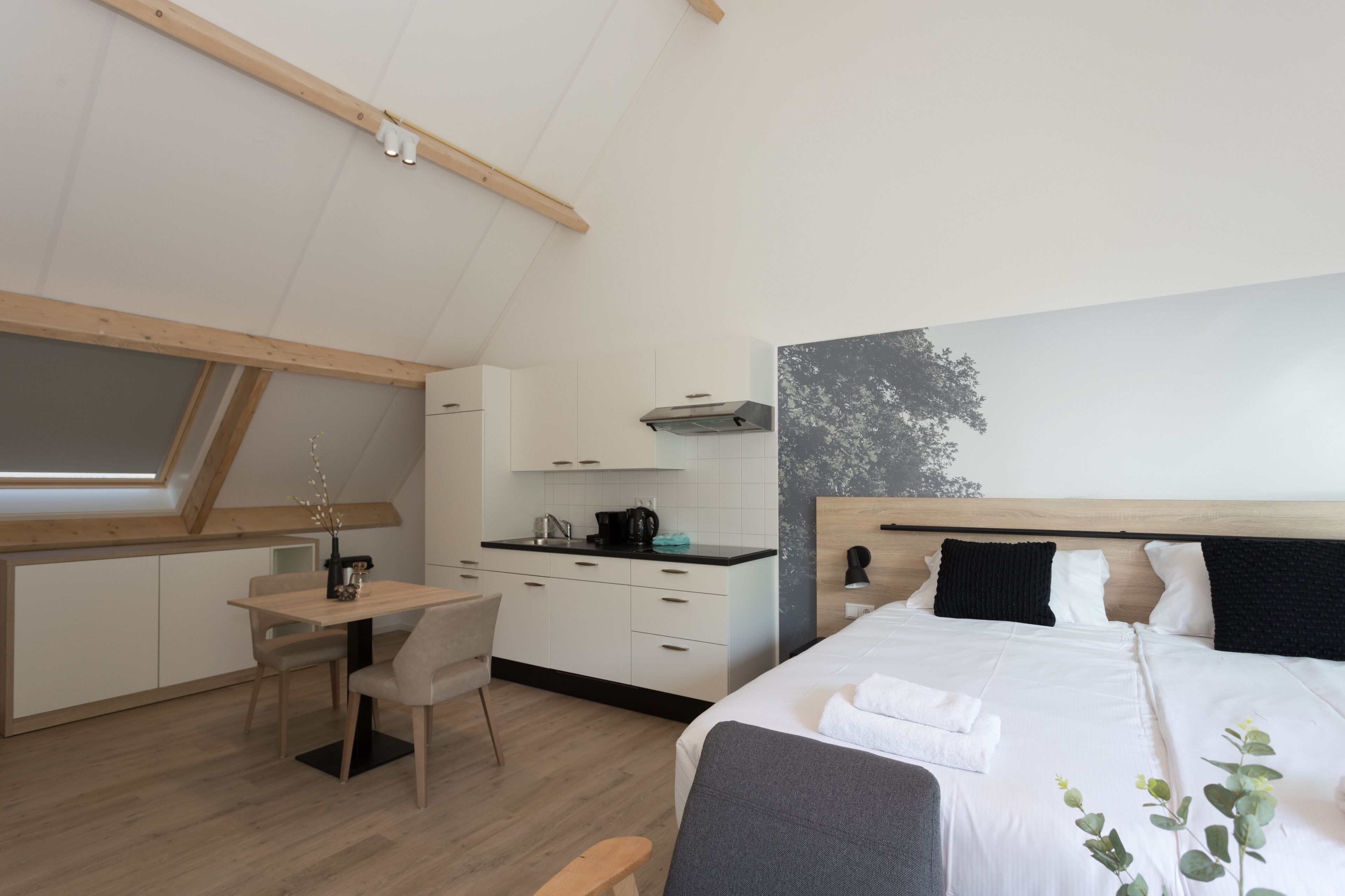 A modern, compact room with a kitchenette, a dining area, and a bed.