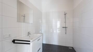 Une salle de bain moderne avec des carreaux blancs, un lavabo, un miroir et une douche.